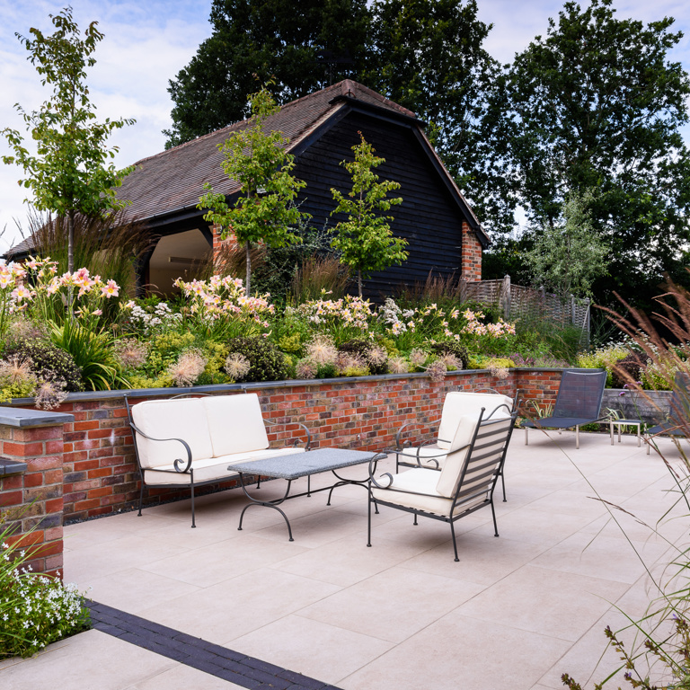 Porcelain paved terrace with brick retaining walls and slate coping