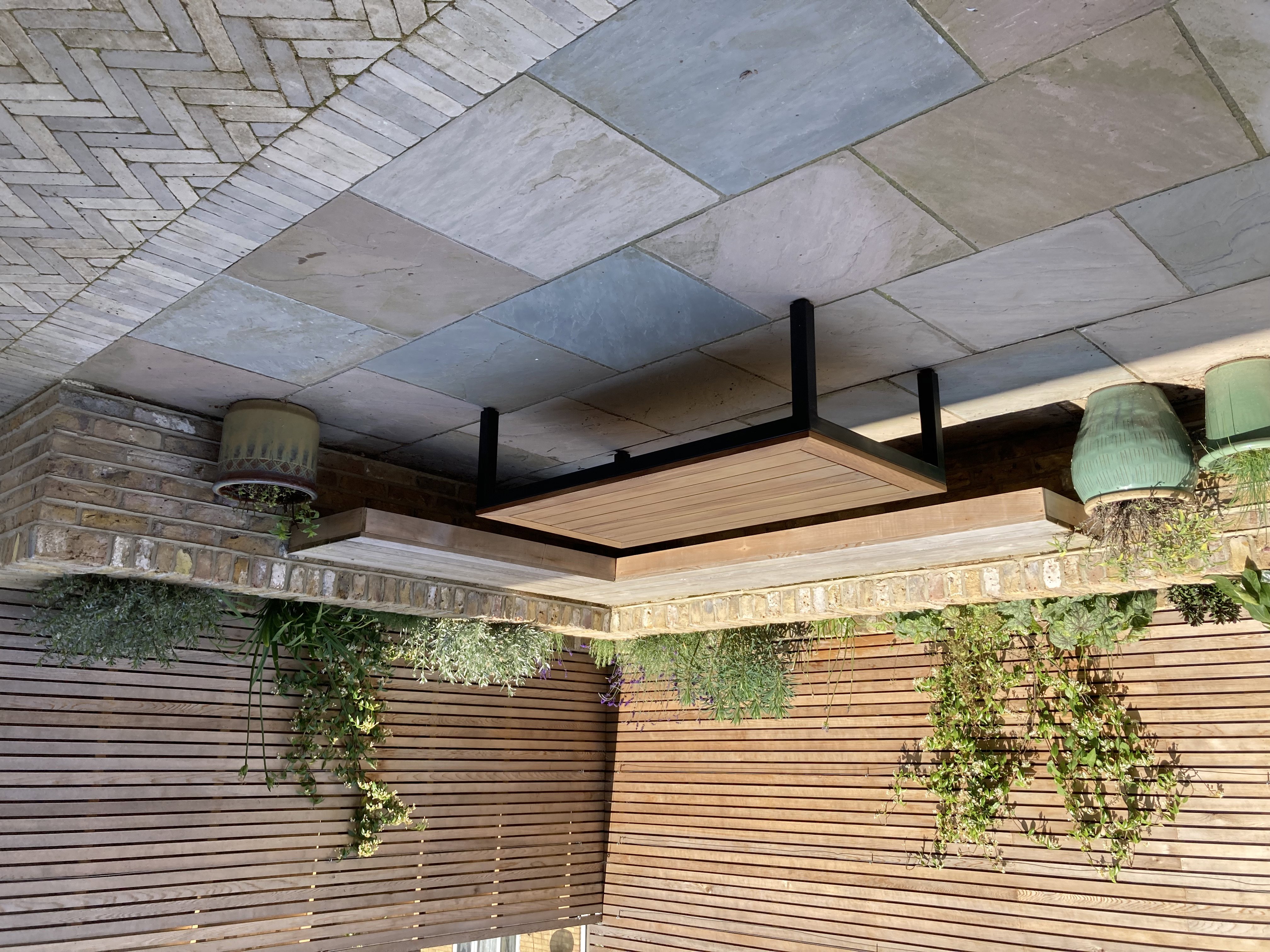 Built-in 'floating' cedar corner bench with brick raised planting border behind