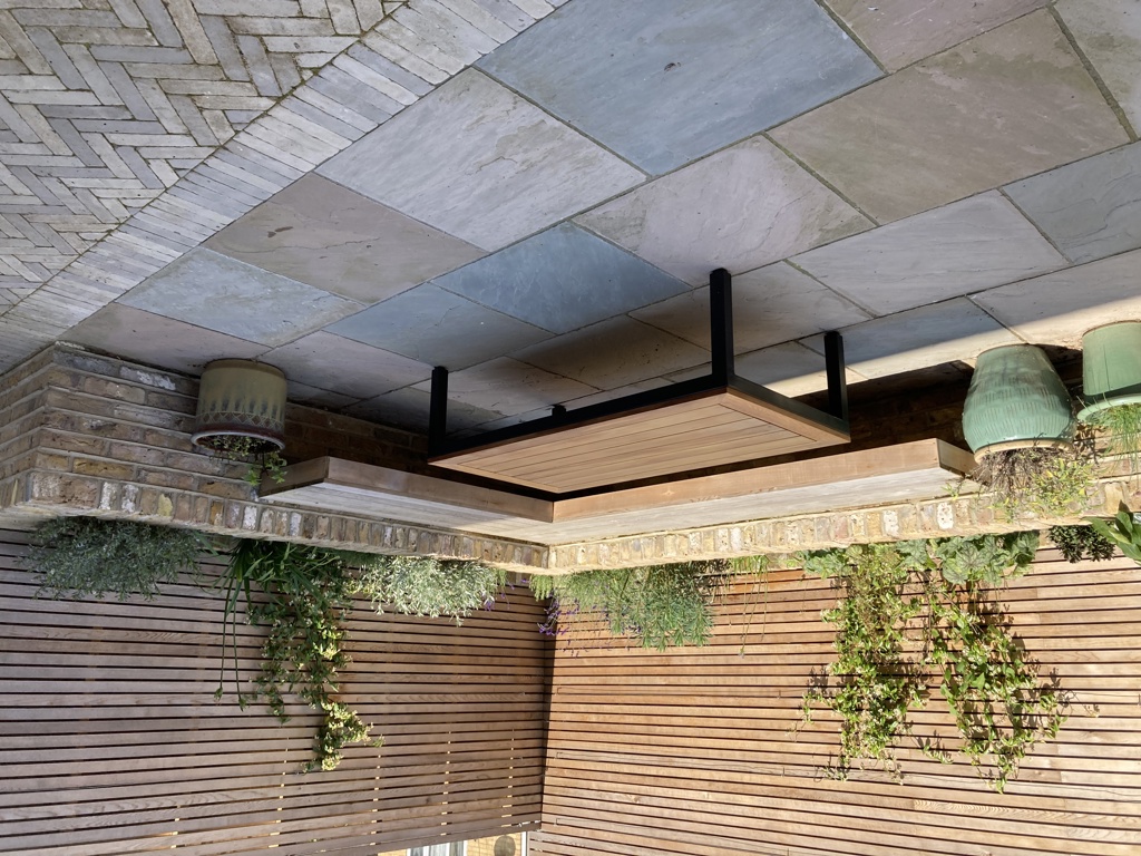 Built-in 'floating' cedar corner bench with brick raised planting border behind
