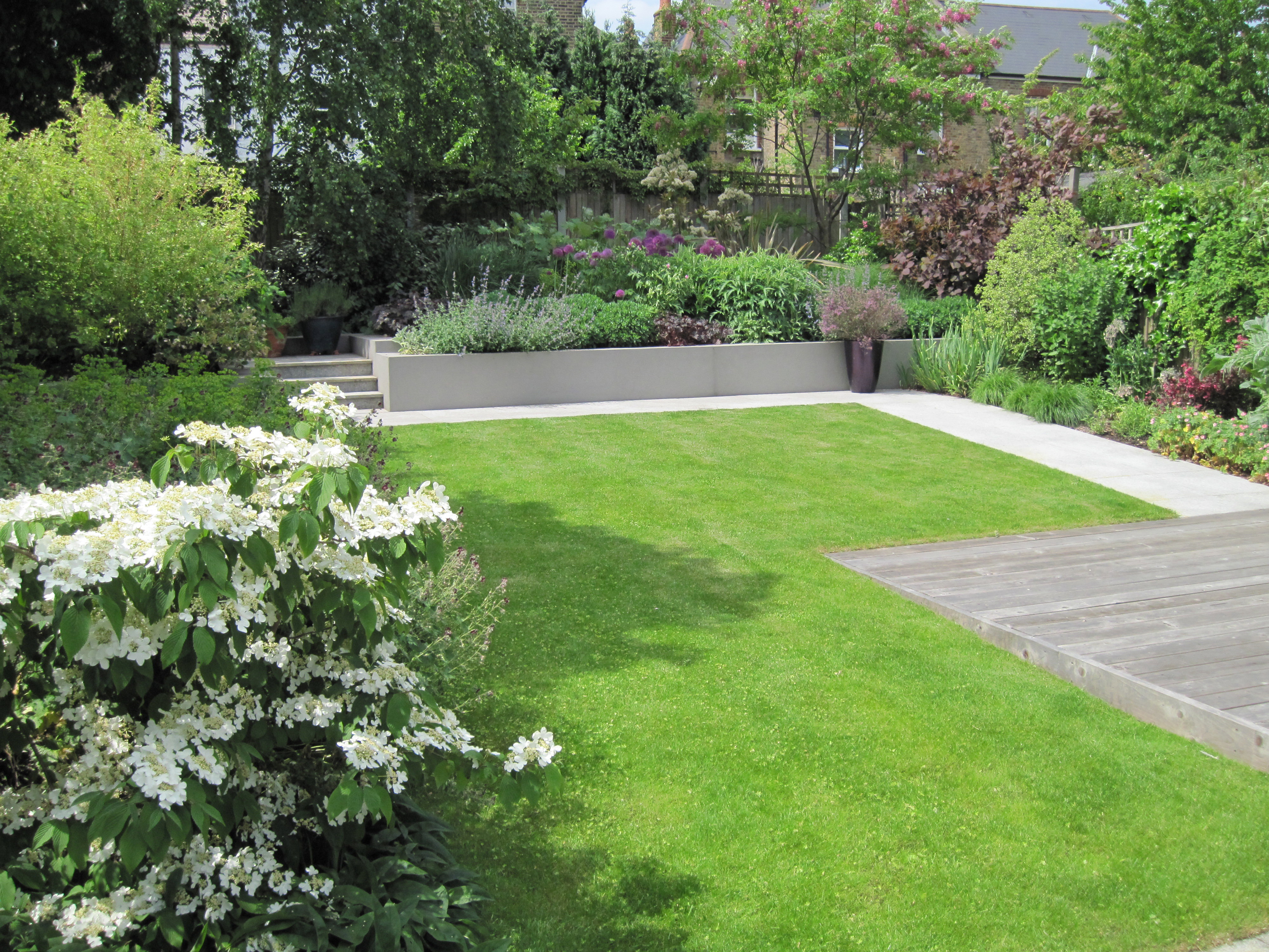 Terraced rear border beyond lawn with deep layered planting