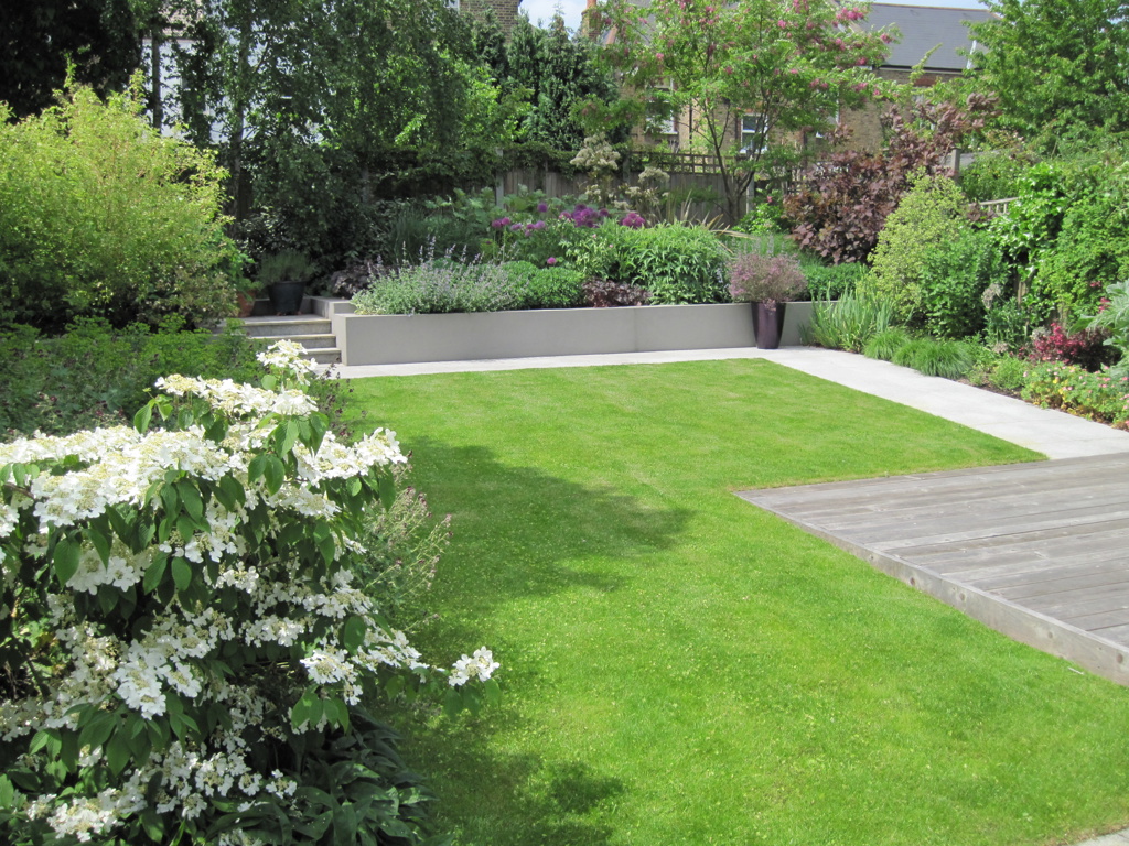 Terraced rear border beyond lawn with deep layered planting